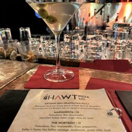 Dirty martini - A classic martini garnished with green olives is placed on a red napkin at Hawt Pizza in Santa Fe, NM, with a bar and drinkware in the background.