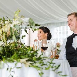 Jamestown Catering - Happy couple smiling at their sweetheart table during an outdoor wedding catered by Jamestown Catering in Wilmington, Delaware.