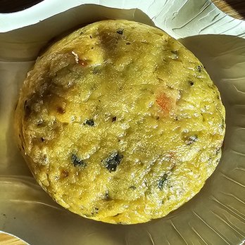Starbucks - Sausage egg bite - A sausage egg bite, a breakfast item, is placed on a foil tray on a wooden surface. - Coffee & Tea Near Me - Leander, Texas