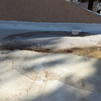 Paramount Roofing - Snow from 6 days ago has been melting. Roof isn't draining, so water freezes up each night - The image shows a flat roof with water stains, cracks, and areas of deterioration, with some shading from trees. - Roofing Near Me - Albuquerque, New Mexico
