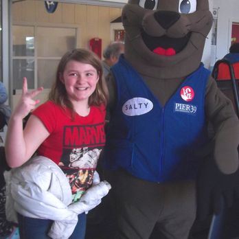 PIER 39 - The girl poses with the mascot, Salty - Shopping Centers Near Me - San Francisco, California