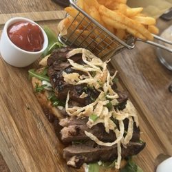 Views Restaurant - Steak sandwich with Maui onion crisps and arugula served open face on sourdough bread with fries.