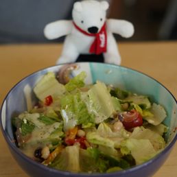 a bowl of salad with a teddy bear in the background a bowl of salad with a teddy bear in the background
