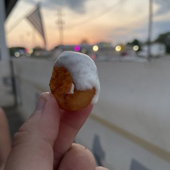 Pullman Tavern - a hand holding a donut with white icing - Pubs Near Me - Pullman, Michigan