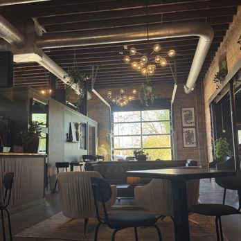 The Alchemist - A cozy coffee and cocktail bar features a wooden interior, modern lighting fixtures, and large windows with natural light. - Coffee & Tea Near Me - Indianapolis, Indiana