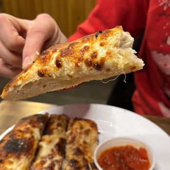 Artisana Pizza - a person holding a slice of pizza - Pizza Near Me - Centreville, Virginia Artisana Pizza - a person holding a slice of pizza - Pizza Near Me - Centreville, Virginia