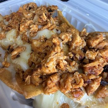 Cali Burrito Co - nachos with chicken 10/10 flavor - A takeout container holds nachos topped with shredded chicken, melted cheese, and crispy tortilla chips, served in a casual setting. - Mexican Near Me - Albuquerque, New Mexico