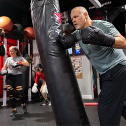 Omni Fight Club Roswell member working the heavy bag during a boxing fitness class, building strength, conditioning, and conf...