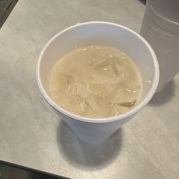 Horchata - A cup of horchata with ice cubes is placed on a table, alongside a glass of water. The setting appears to be casual, possibly at a restaurant or cafe.