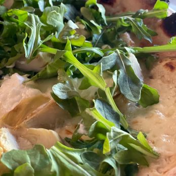 Leña - a close up of a pizza with greens on it - Pizza Near Me - Cleveland, Mississippi