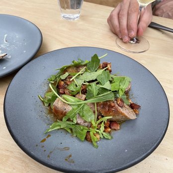 Runner Up - Sausage dish was good - A dish featuring cooked meat garnished with fresh arugula and small diced vegetables, served on a black plate at a restaurant. - French Near Me - Brooklyn, New York