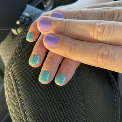 Stop 4 Nails - Kiddo hand with teal and sparkly gel manicure, adult hand with purple gel manicure.