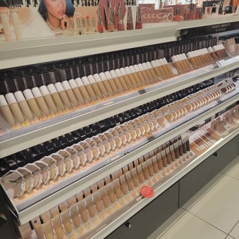 Kohl's - A cosmetics store shelf showcases a range of foundation and concealer products in different shades, with promotional images and makeup tools above. - Department Stores Near Me - DEPEW, New York