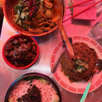 Mala Project - Sweet & Sour Pork Ribs, Left Over Fried Rice., MALA DRY POT (build your own combo) and DnDn Noodlesnoodles - The image shows a metal table with a variety of Chinese dishes. There is a bowl of plain noodles topped with minced meat, a plate of fried rice with broccoli, and a bowl of stir-fried vegetables with chili peppers and cilantro. Chopsticks and utensils are placed on the table, along with a glass of water and a pink napkin. The setting appears to be a restaurant with a casual dining atmosphere. - Chinese Near Me - Brooklyn, New York