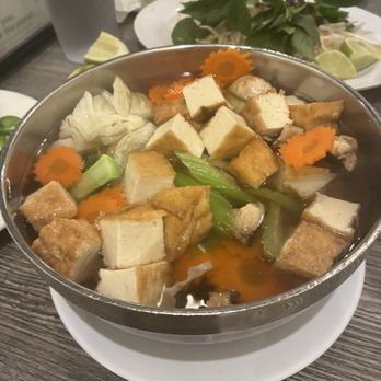 Pho Minh - A bowl of Vietnamese noodle soup features tofu, carrots, cabbage, and green onions in broth, with fresh herbs and lime on the side. - Soup Near Me - Temecula, California