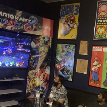 Game Night - People playing Mario Kart and the nostalgic Super Mario 3 poster on the wall - Bars Near Me - Coral Springs, Florida Game Night - People playing Mario Kart and the nostalgic Super Mario 3 poster on the wall - Bars Near Me - Coral Springs, Florida