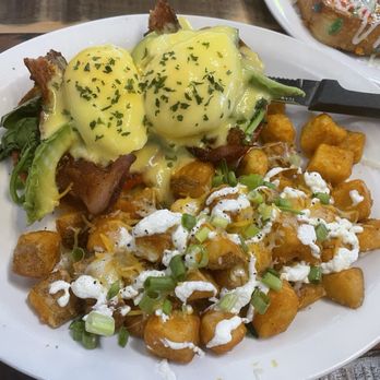 Biscuits Cafe - Beast Benedict - Eggs Benedict with hollandaise sauce, hash browns, and green onions on a white plate. - Breakfast & Brunch Near Me - Glendale, Arizona