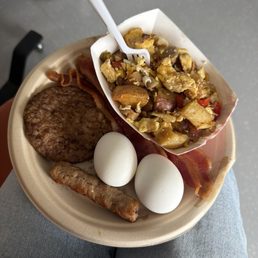 Breakfast sausage, boiled eggs, bacon strips, sausage patty, s rambled eggs with vegetables and potatoes