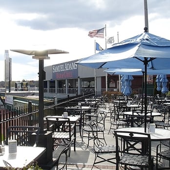 The Patio - Patio tables, the Samuel Adams Bar & Grill (inside the park) can be seen in the background - Bars Near Me - Manchester, New Hampshire The Patio - Patio tables, the Samuel Adams Bar & Grill (inside the park) can be seen in the background - Bars Near Me - Manchester, New Hampshire