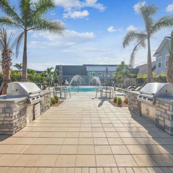 Palm Grove Luxury Apartments - A grill station with a pool in the background - Apartments Near Me - Ellenton, Florida Palm Grove Luxury Apartments - A grill station with a pool in the background - Apartments Near Me - Ellenton, Florida