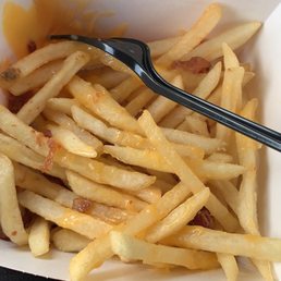 a fork in a container of french fries a fork in a container of french fries