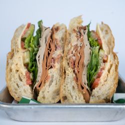 Glowing - BLT Sandwich: Vegan bacon, vegan turkey, vegan ham, vegan cheese, seasonal greens, tomato, pickles, onions and BLT sauce on toasted ciabatta