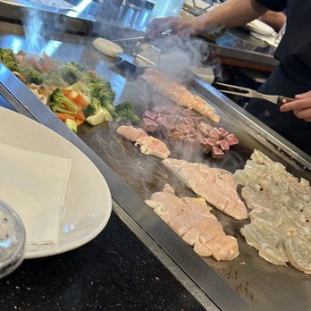 Sakura Sushi & Hibachi - a man cooking food on a grill - Sushi Bars Near Me - Semmes, Alabama