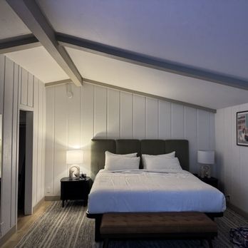 The Marlo - A king sized bed with a large tv hanging on the wall and two bedside tables - Hotels Near Me - Solvang, California The Marlo - A king sized bed with a large tv hanging on the wall and two bedside tables - Hotels Near Me - Solvang, California