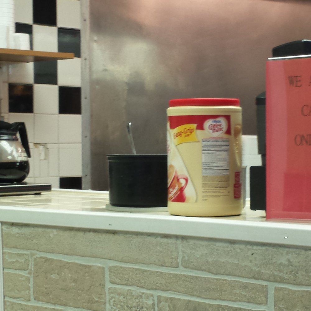 Green's Carryout - a coffee machine and a sign on a counter - American Near Me - Baltimore, Maryland Green's Carryout - a coffee machine and a sign on a counter - American Near Me - Baltimore, Maryland