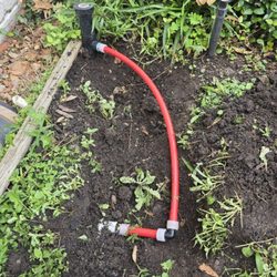 J & G Plumbing Services - This image showcases a sprinkler system repair featuring a red PEX pipe with elbow fittings connecting to a sprinkler head...