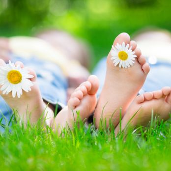 iCare Lawn Care - a person laying in the grass with two daisies on their feet - Lawn Services Near Me iCare Lawn Care - a person laying in the grass with two daisies on their feet - Lawn Services Near Me