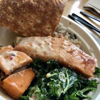 Urbane Cafe - Urbane Cafe: 40688 Winchester Rd, Temecula, CA 92591, 20220206 - A takeout container holds salmon, kale, sweet potatoes, rice, and a cracker, with utensils and napkins visible nearby. - Sandwiches Near Me - Temecula, California