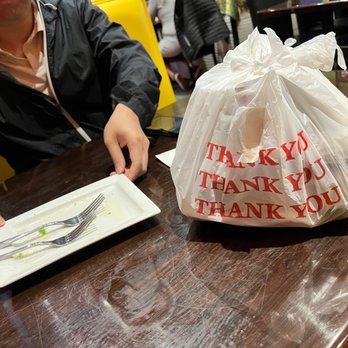 Thai Rainbow - a woman sitting at a table with a bag of food - Thai Near Me - Middle River, Maryland Thai Rainbow - a woman sitting at a table with a bag of food - Thai Near Me - Middle River, Maryland