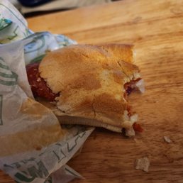 a half eaten sandwich on a wooden table