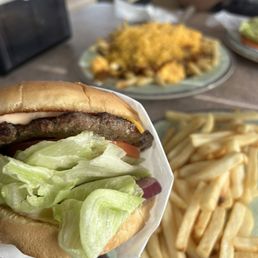 Cheeseburger with fries and chili cheese fries in the background Cheeseburger with fries and chili cheese fries in the background