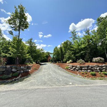 BG Land Care - a driveway with a stone wall and trees in the background - Lawn Services Near Me