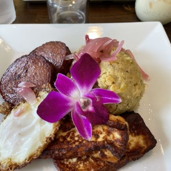 Richie’s Kitchen - Los tres golpes (mangú, queso frito, huevo frito, y salchichas dominicanas) - A plate featuring fried plantains, a potato ball, fried cheese, and a fried egg, garnished with a purple orchid. - Latin American Near Me - Ossining, New York