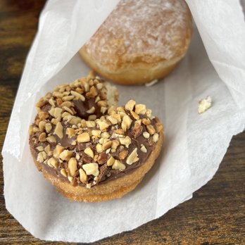Donut Capital - two donuts. one has chocolate and peanuts, and the other has powdered sugar and a lemon jelly filling - Donuts Near Me - Paramount, California Donut Capital - two donuts. one has chocolate and peanuts, and the other has powdered sugar and a lemon jelly filling - Donuts Near Me - Paramount, California