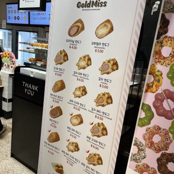 Gold Miss - a woman standing in front of a display of pastries - Hot Dogs Near Me - Fairfax, Virginia Gold Miss - a woman standing in front of a display of pastries - Hot Dogs Near Me - Fairfax, Virginia