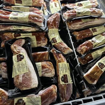 Hermann Wurst Haus - Bacon - Various packages of smoked bacon are arranged in a refrigerated display, each with labels indicating the product type and weight. - Meat Shops Near Me - Hermann, Missouri