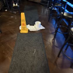 Bucket, catching water from a leaking ceiling, in my the middle of the main walkway between dining area and bar seating.