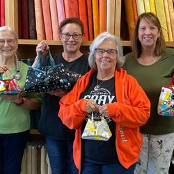 Students proudly display their handmade fabric purses after a Decorative Stitch class. This creative sewing workshop focused ...