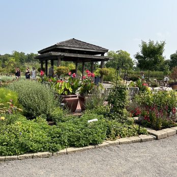 Cantigny - A landscaped garden with a wooden pavilion, potted plants, and flowering beds at Cantigny Park, Wheaton, IL, with visitors walking and relaxing. - Museums Near Me - Wheaton, Illinois