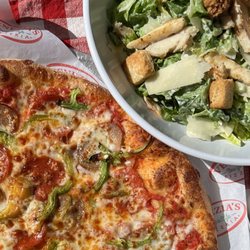 Venezia's New York Style Pizzeria - Large Cesear Salad with buttery croutons and grilled chicken next to a large and fresh pizza with pepperoni sausage and peppers.