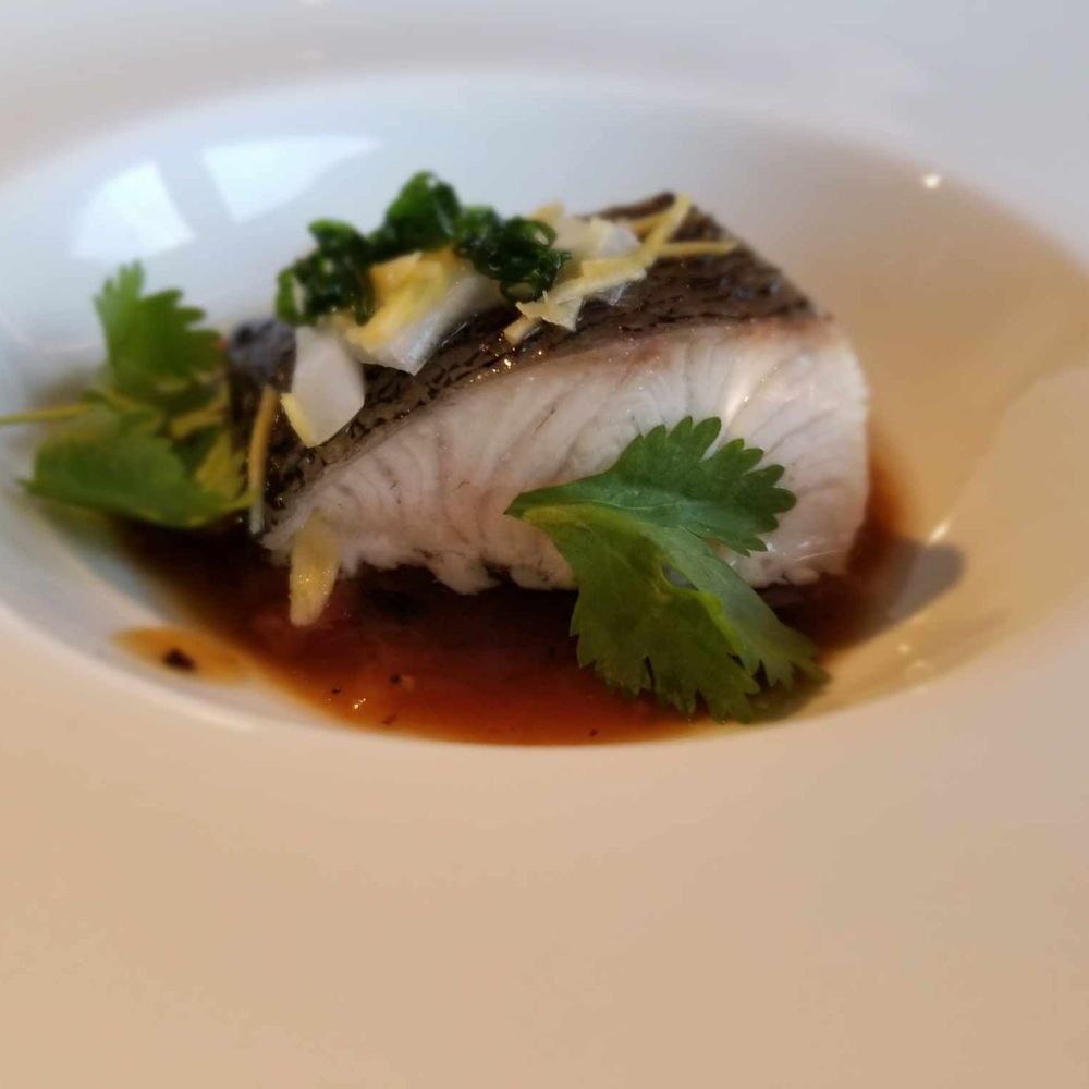 Naʻau - a white plate with a piece of fish and garnish - Hawaiian Near Me Naʻau - a white plate with a piece of fish and garnish - Hawaiian Near Me