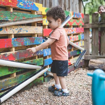 Headwaters School - This Young Children's Casita (YCC) student is playing in the classroom's courtyard and experimenting with a ball rolling. - Preschools Near Me - Austin, Texas