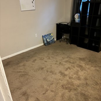 Reasonable Movers - A mostly empty room features a small whiteboard on the wall, a painting of Van Gogh's Starry Night on the floor, and a black shelving unit with a TV and an electric kettle. - Movers Near Me