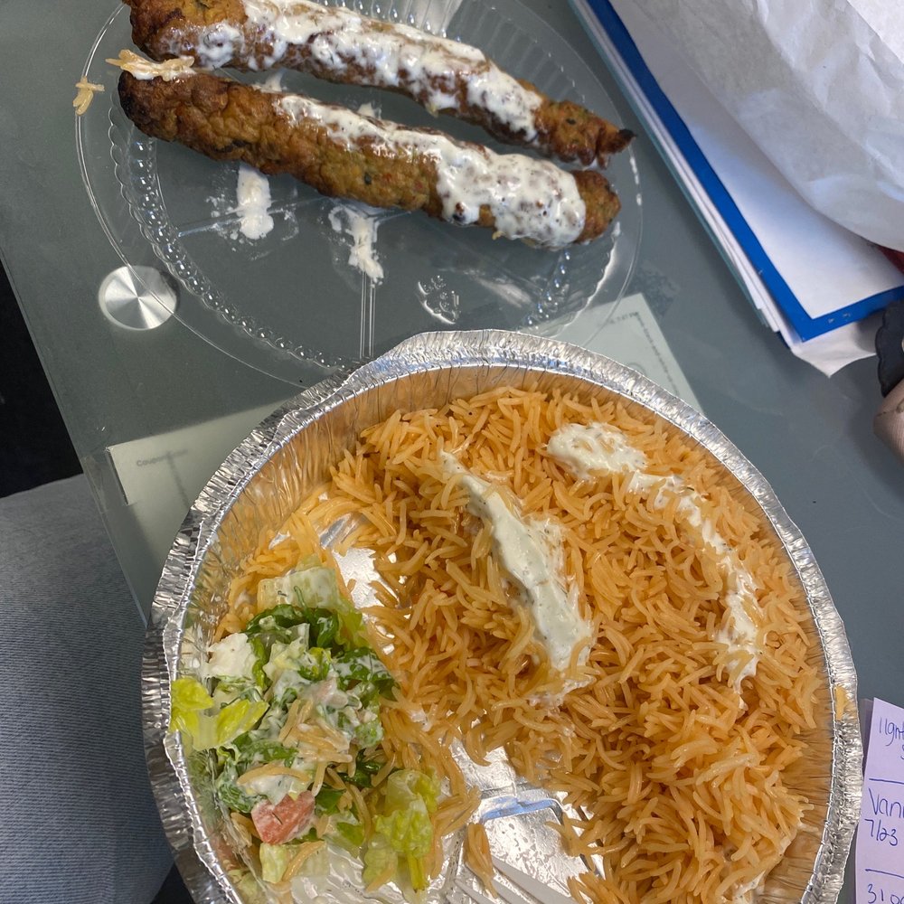 Chicken Kabob over rice with a salad and white sauce