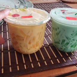 a person's hand holding two cups of iced tea