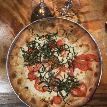 Bagalis - a pizza with tomatoes and spinach - Italian Near Me - Frisco, Colorado Bagalis - a pizza with tomatoes and spinach - Italian Near Me - Frisco, Colorado